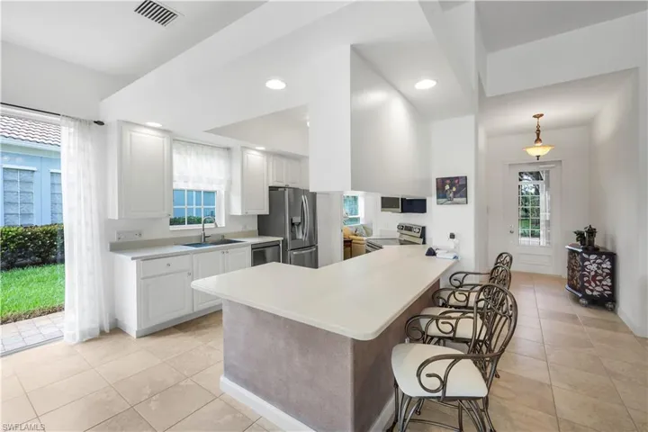 Kitchen featuring light countertops, a breakfast bar, appliances with stainless steel finishes, a peninsula, and recessed lighting