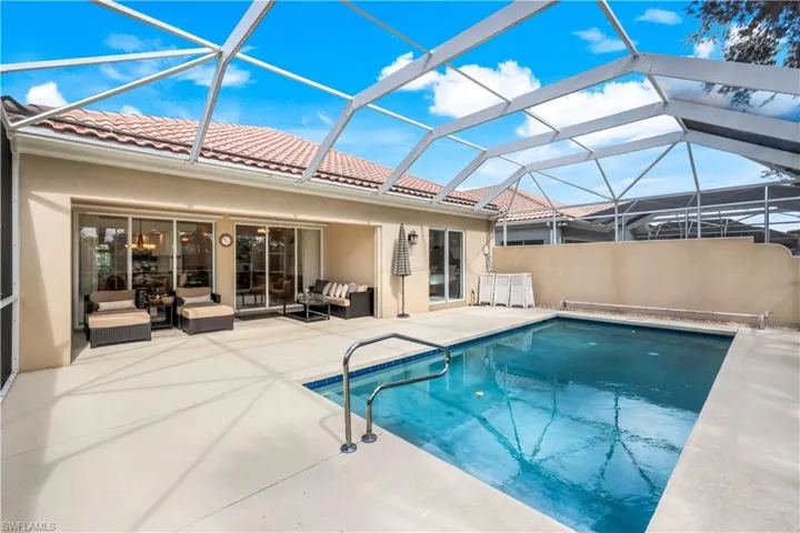 Outdoor pool with a sunroom, a patio area, glass enclosure, and an outdoor hangout area