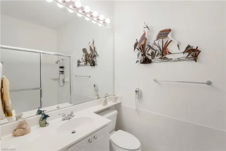 Bathroom featuring vanity, a shower stall, and tile walls