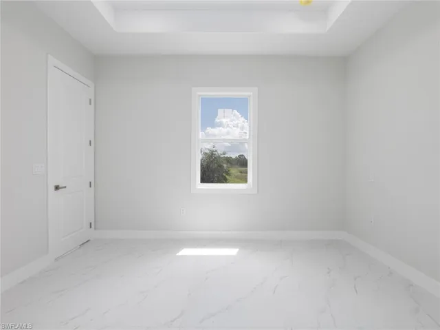 Bedroom with a tray ceiling and light tile patterned floors