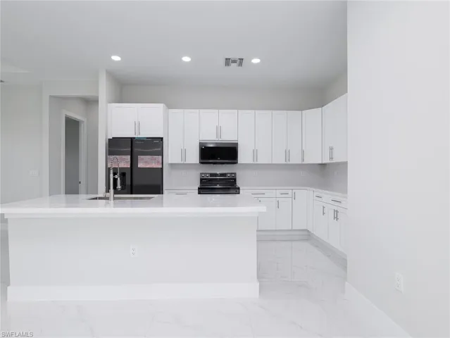 Kitchen with a center island with sink, range with electric cooktop, and light tile patterned floors