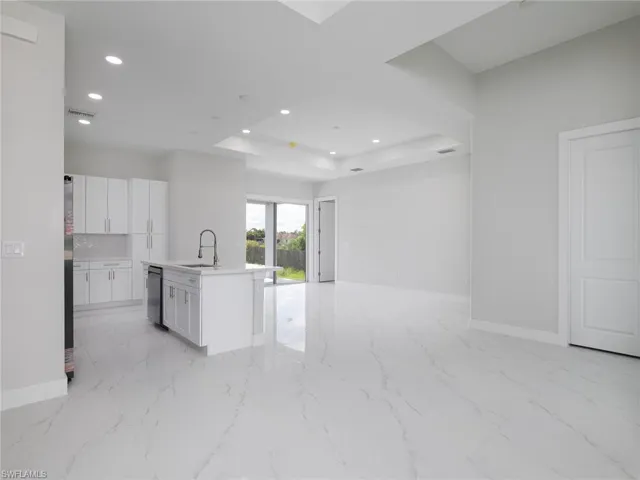 Kitchen featuring decorative backsplash, light tile patterned floors, and a kitchen island with sink