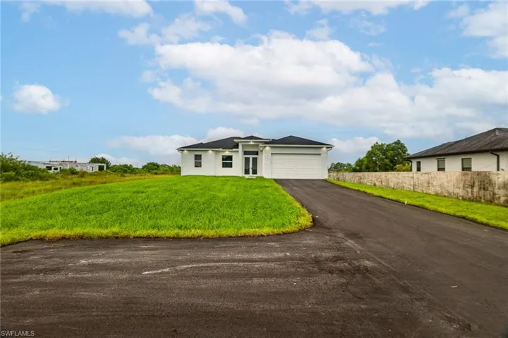 View of front facade featuring a front lawn and a garage