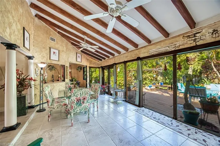 Unfurnished sunroom featuring decorative columns, lofted ceiling with beams, and ceiling fan