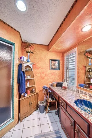 Bathroom featuring tile patterned floors, beamed ceiling, sink, a textured ceiling, and walk in shower