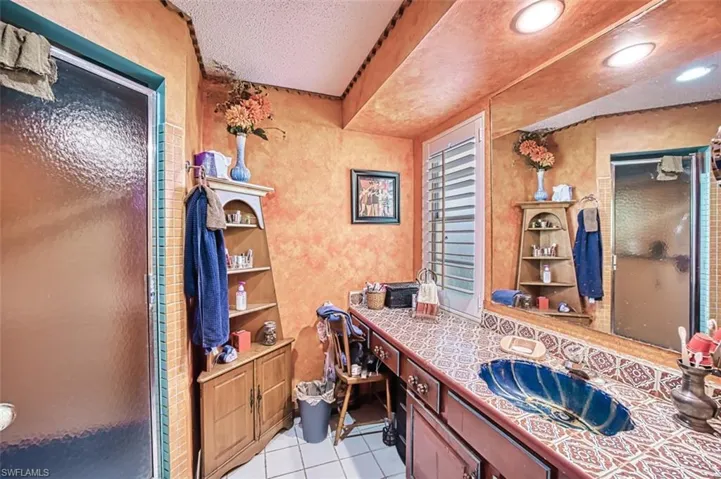 Bathroom featuring vanity, a textured ceiling, a shower with shower door, and tile patterned floors
