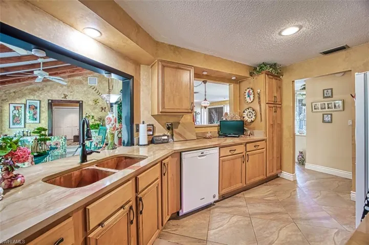 Kitchen with sink, dishwasher, a textured ceiling, ceiling fan, and vaulted ceiling