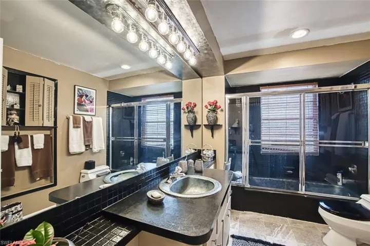 Full bathroom with vanity, toilet, combined bath / shower with glass door, and plenty of natural light