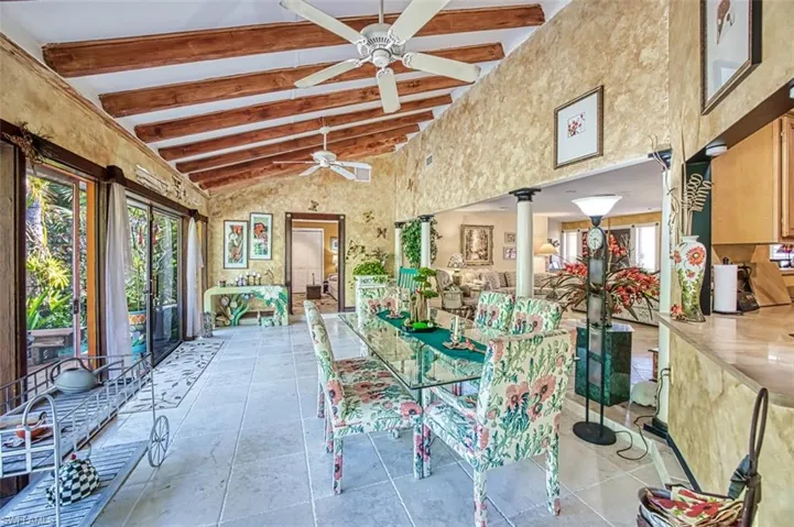 Unfurnished dining area featuring decorative columns, ceiling fan, beamed ceiling, high vaulted ceiling, and light tile patterned floors
