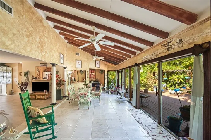 Unfurnished sunroom with plenty of natural light, ceiling fan, and vaulted ceiling with beams