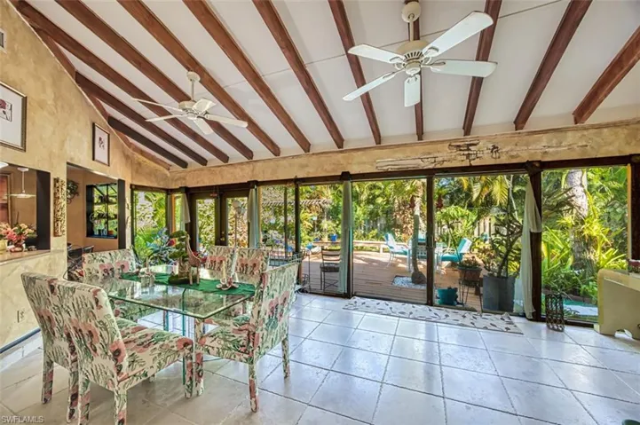 Unfurnished sunroom featuring vaulted ceiling with beams and ceiling fan