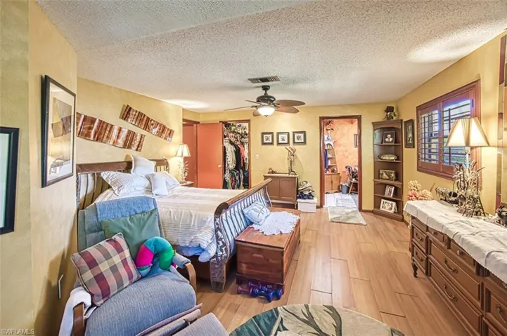 Bedroom featuring a closet, a textured ceiling, light hardwood / wood-style floors, and ceiling fan