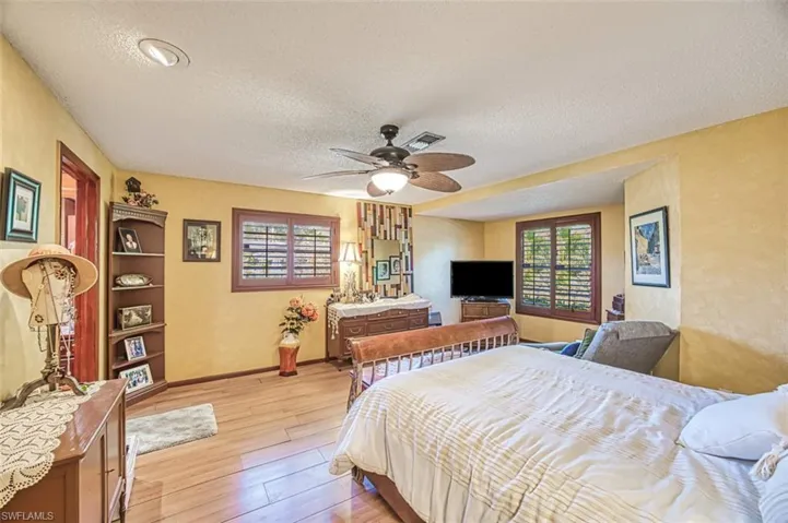 Bedroom with ceiling fan, a textured ceiling, and light hardwood / wood-style flooring