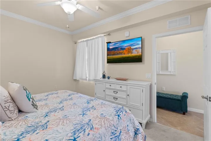 Bedroom with visible vents, crown molding, baseboards, light colored carpet, and ceiling fan
