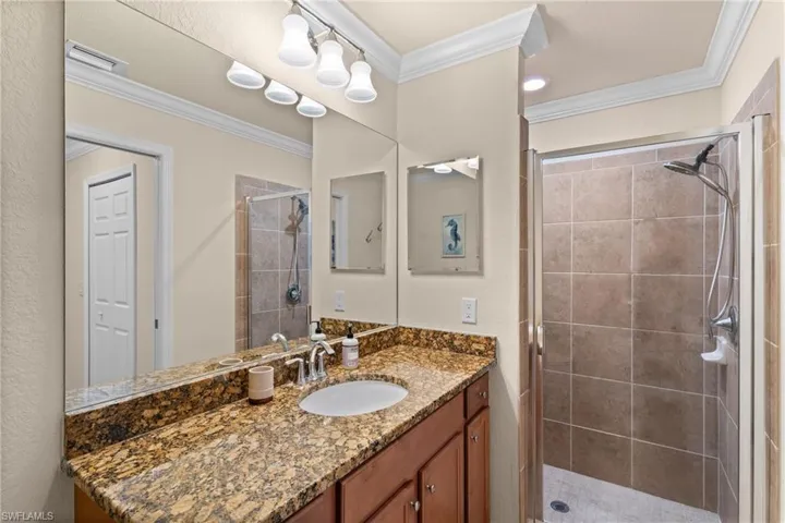 Bathroom with vanity, crown molding, visible vents, and a stall shower
