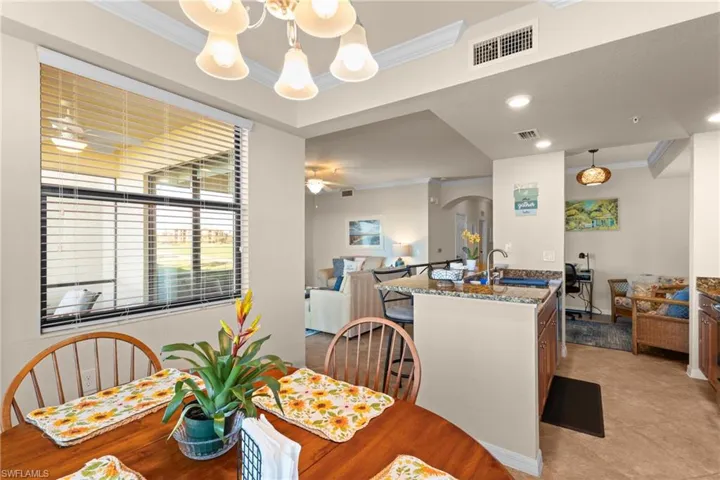 Dining space with arched walkways, visible vents, ceiling fan with notable chandelier, and crown molding
