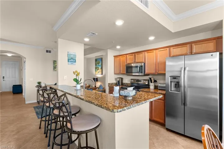 Kitchen with visible vents, appliances with stainless steel finishes, a kitchen breakfast bar, and ornamental molding