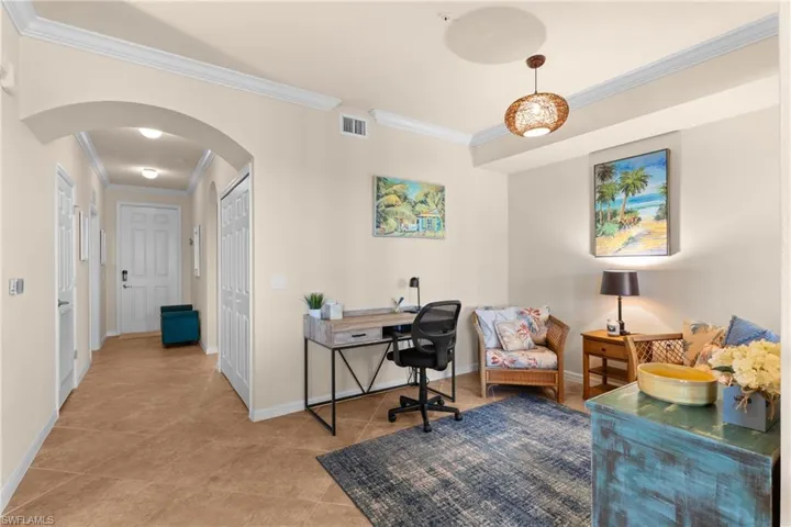 Office area featuring arched walkways, tile patterned flooring, baseboards, and ornamental molding