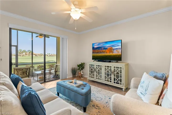 Tiled living room with ornamental molding, baseboards, and ceiling fan