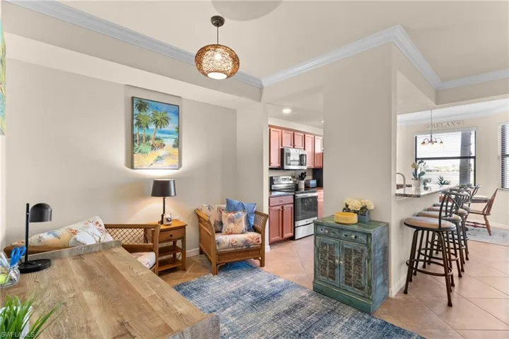 Living area featuring light tile patterned floors, a chandelier, baseboards, and ornamental molding