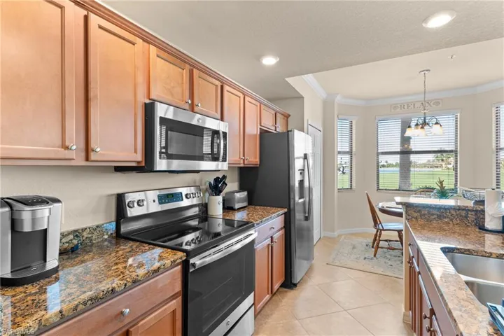 Kitchen with a chandelier, brown cabinets, appliances with stainless steel finishes, and ornamental molding