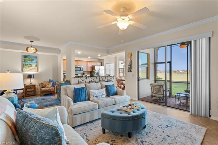 Living area featuring ornamental molding, light tile patterned floors, baseboards, and ceiling fan