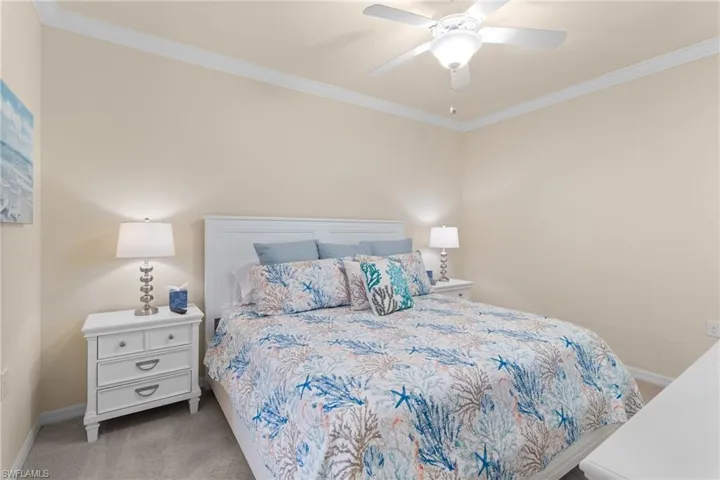 Carpeted bedroom with ceiling fan, baseboards, and ornamental molding