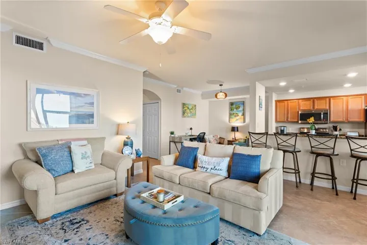 Living room with visible vents, recessed lighting, arched walkways, ceiling fan, and crown molding