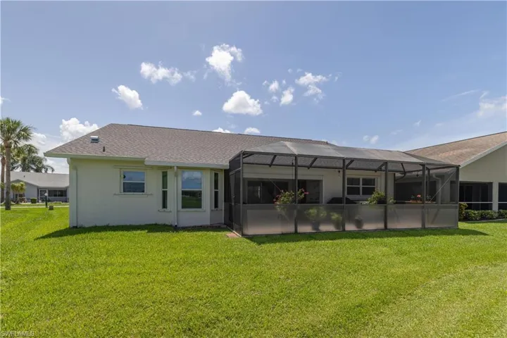 Back of property with glass enclosure and a yard
