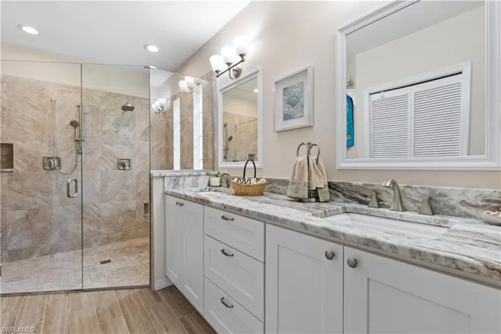 Bathroom with a shower with shower door, lofted ceiling, and double sink vanity