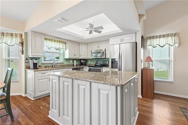 Kitchen with appliances with stainless steel finishes, a center island, a healthy amount of sunlight, and hardwood / wood-style floors