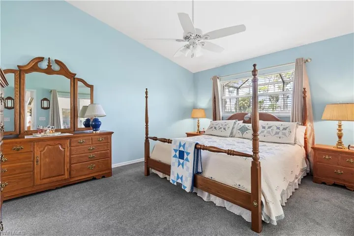 Bedroom with carpet, ceiling fan, and vaulted ceiling