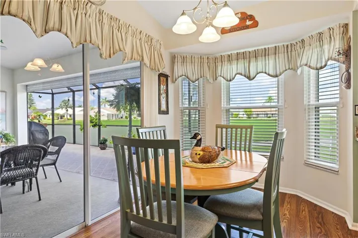 Dine in Kitchen with lofted ceiling, hardwood / wood-style flooring, a notable chandelier, and a healthy amount of sunlight