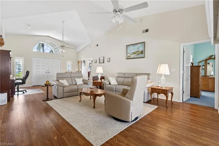 Living room with carpet floors, high vaulted ceiling, and ceiling fan