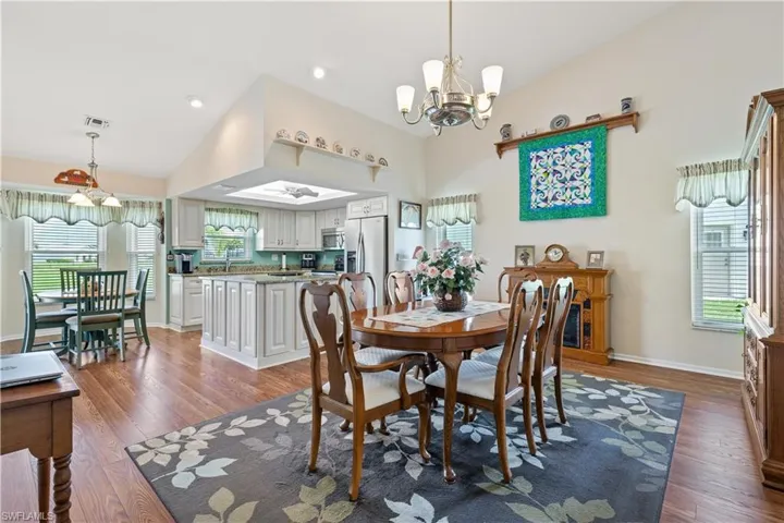 Dining space featuring an inviting chandelier, lofted ceiling, and dark wood-type flooring