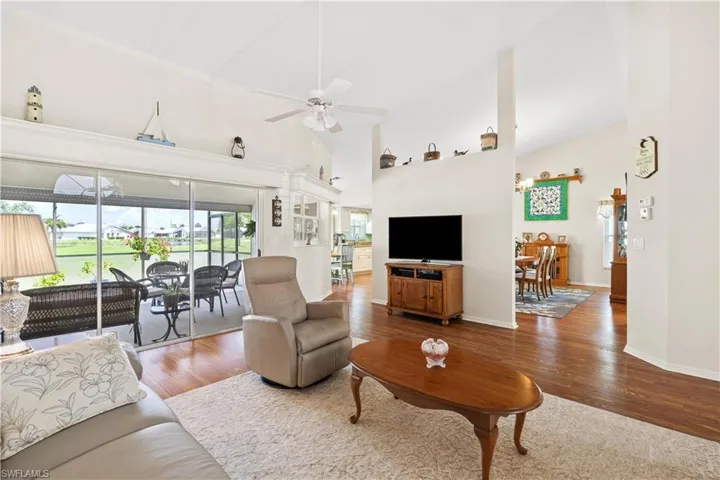 Living room featuring wood-type flooring, ceiling fan, and high vaulted ceiling