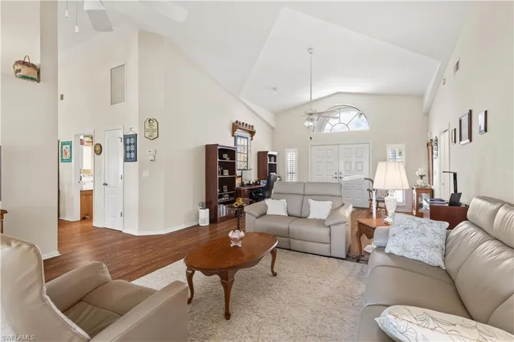 Living room with hardwood / wood-style floors, high vaulted ceiling, and ceiling fan