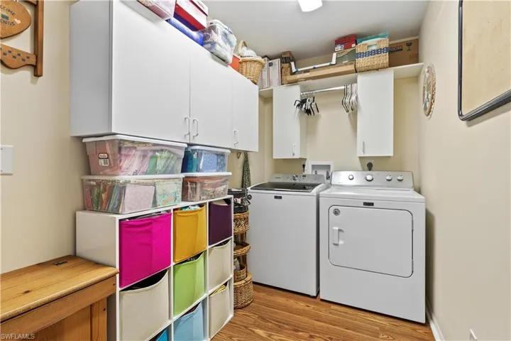 Clothes washing area featuring independent washer and dryer, light wood-type flooring, and cabinets