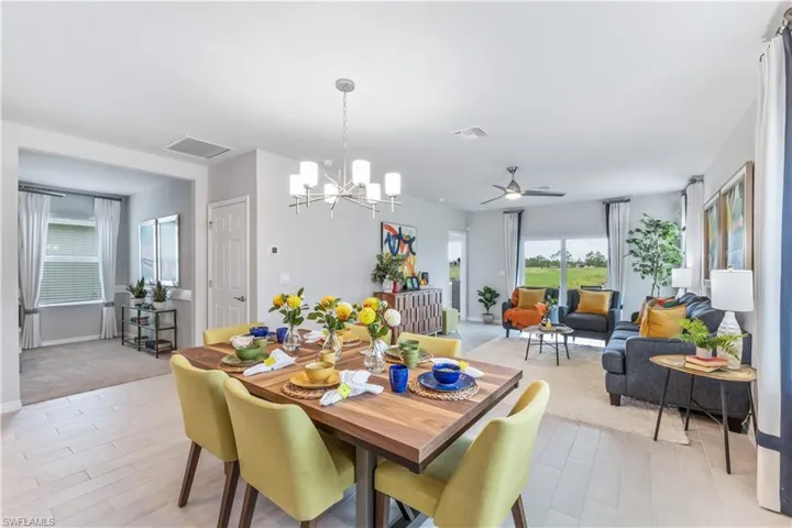 Dining room featuring ceiling fan with notable chandelier and light carpet