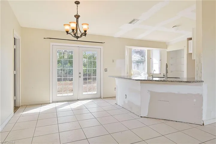 Kitchen with suspended lighting, french doors, dark stone countertops, and light tile patterned floors