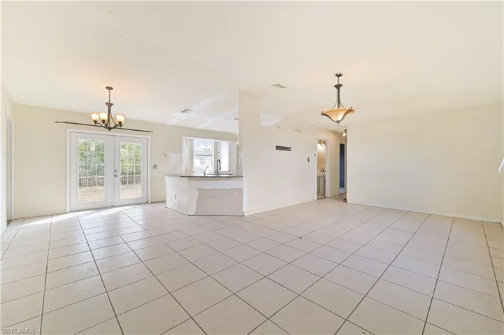 Unfurnished living room with hanging lights, french doors, and light tile patterned floors