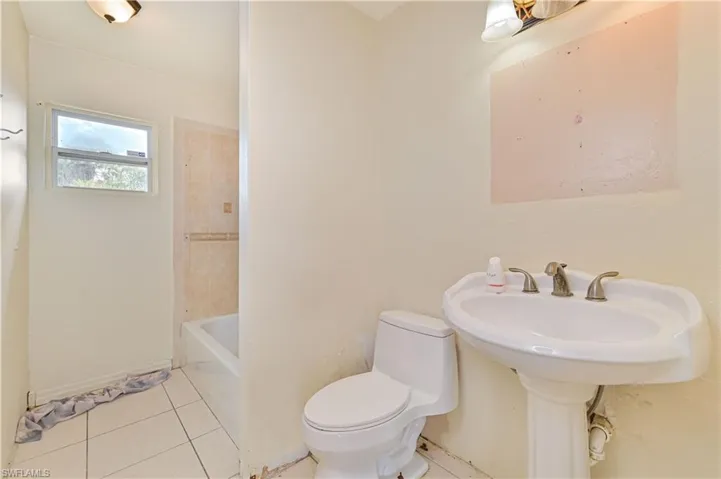 Full bath with light tile patterned floors and shower / washtub combination