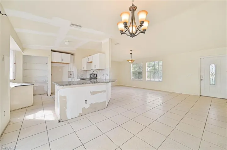 Kitchen with white cabinets, open floor plan, dark stone countertops, suspended lighting, and light tile patterned floors