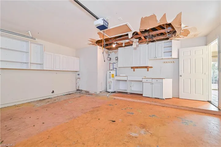 Garage featuring electric water heater and a garage door opener