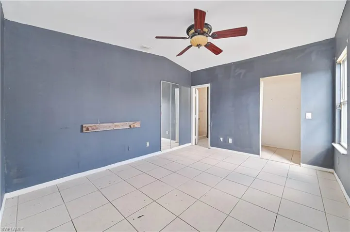 Unfurnished bedroom featuring lofted ceiling, a ceiling fan, a closet, and light tile patterned flooring
