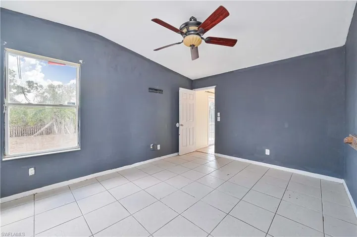 Empty room featuring vaulted ceiling, a ceiling fan, and light tile patterned floors