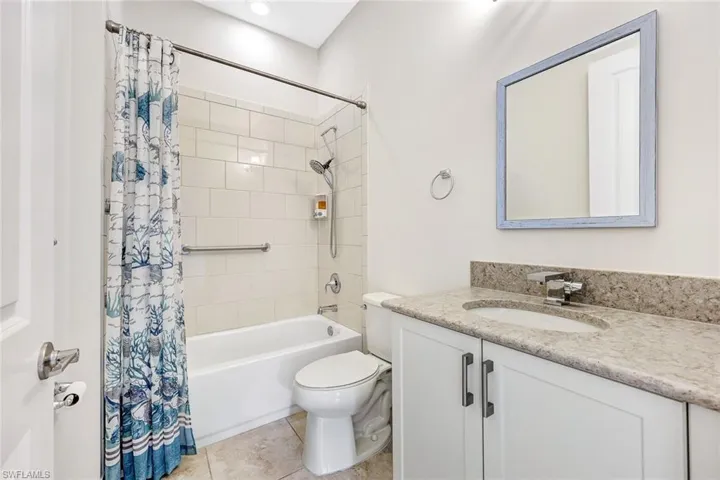 Full bathroom featuring shower / bathtub combination with curtain, vanity, toilet, and tile patterned floors