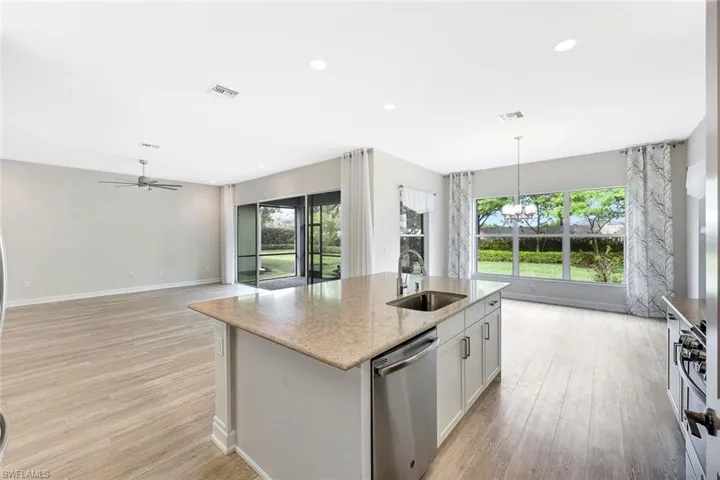 Kitchen with sink, decorative light fixtures, stainless steel dishwasher, an island with sink, and white cabinets