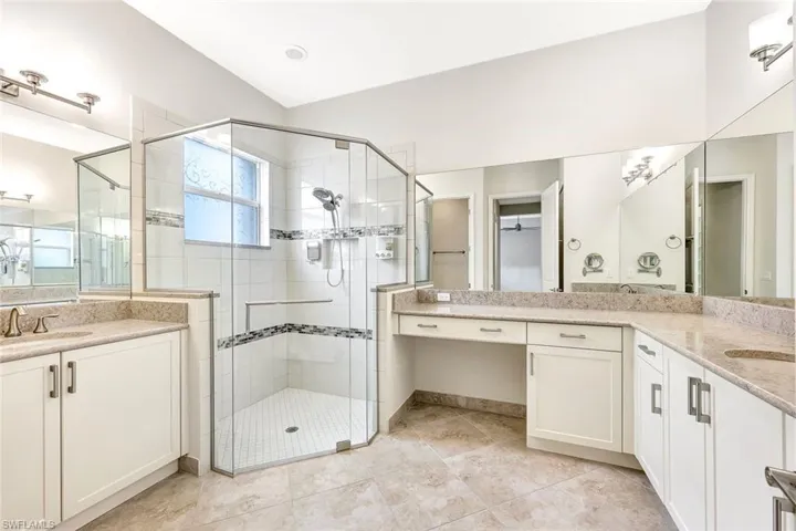 Bathroom with tile patterned floors, lofted ceiling, a shower with door, and vanity