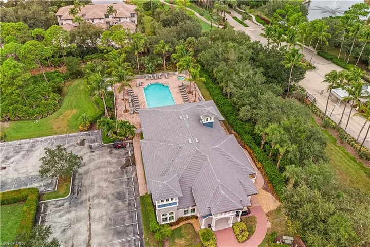 Aerial view of a community clubhouse and pool area and a tree filled landscape